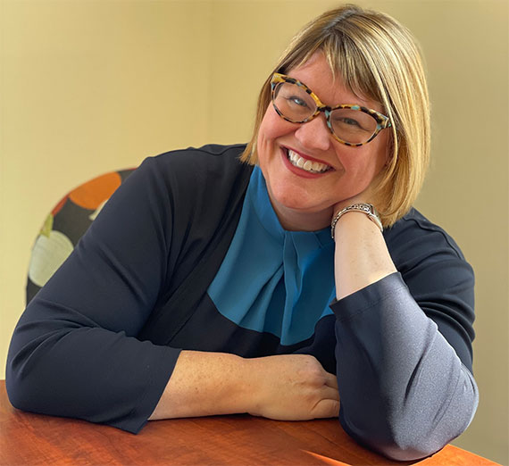 Un groupe de cinq personnes se tient ensemble dans un couloir d’hôpital bien éclairé, en souriant à l’objectif. Deux portent un stéthoscope et des vêtements médicaux, une porte un sweat à capuche de l’université Gonzaga, et les autres sont vêtus de vêtements décontractés ou professionnels, représentant un mélange d’étudiants et de professionnels de la santé.